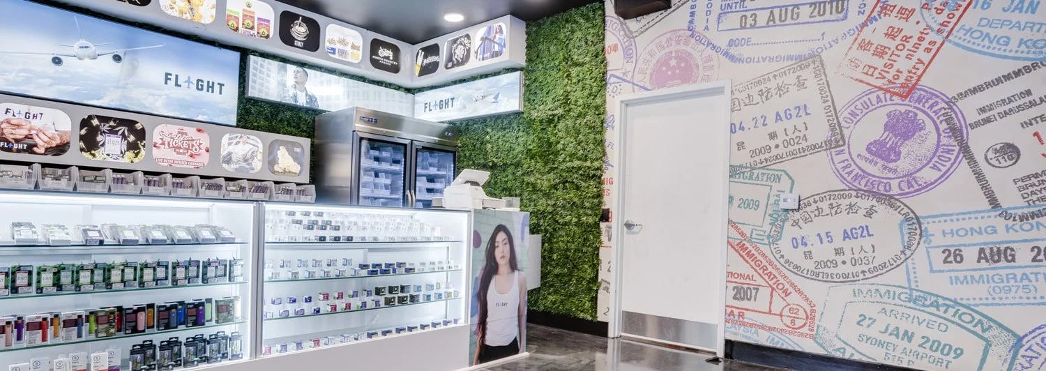 Passport stamp mural wall, living wall, and cannabis product shelves inside Flight SF Dispensary